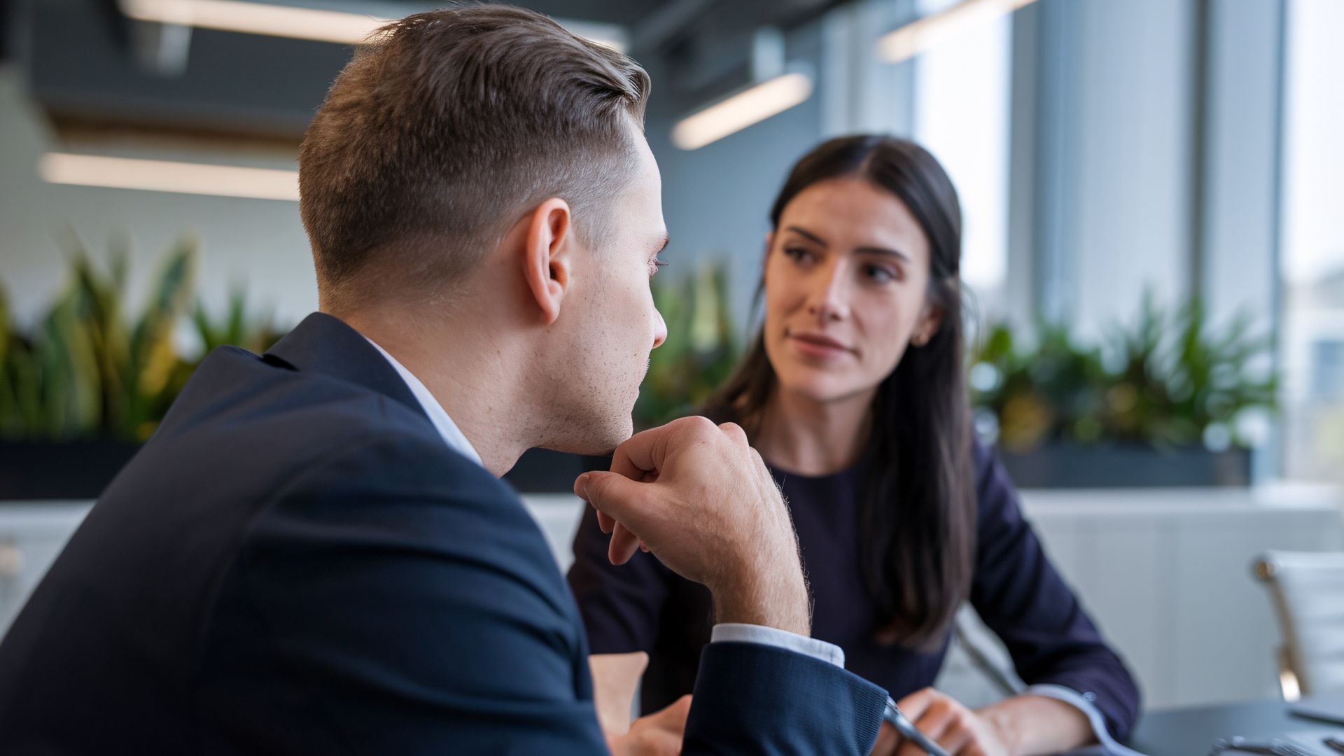 A man and woman sit across from each other in a modern office setting, engaged in a serious conversation, possibly discussing legal matters such as divorce in Nevada.